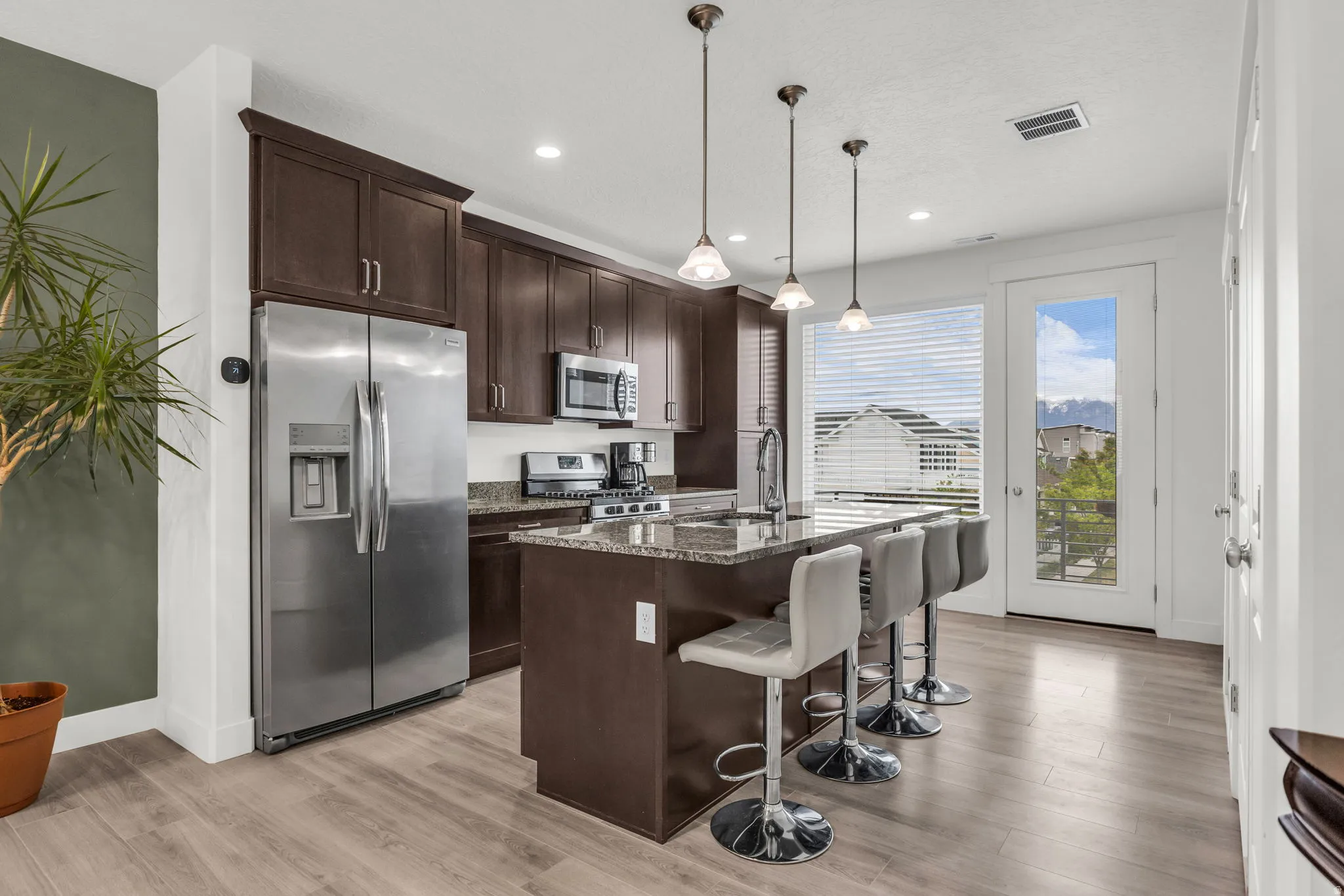 Kitchen featuring dark wood-finish cabinetry, stainless steel appliances, and an island with a stone countertop