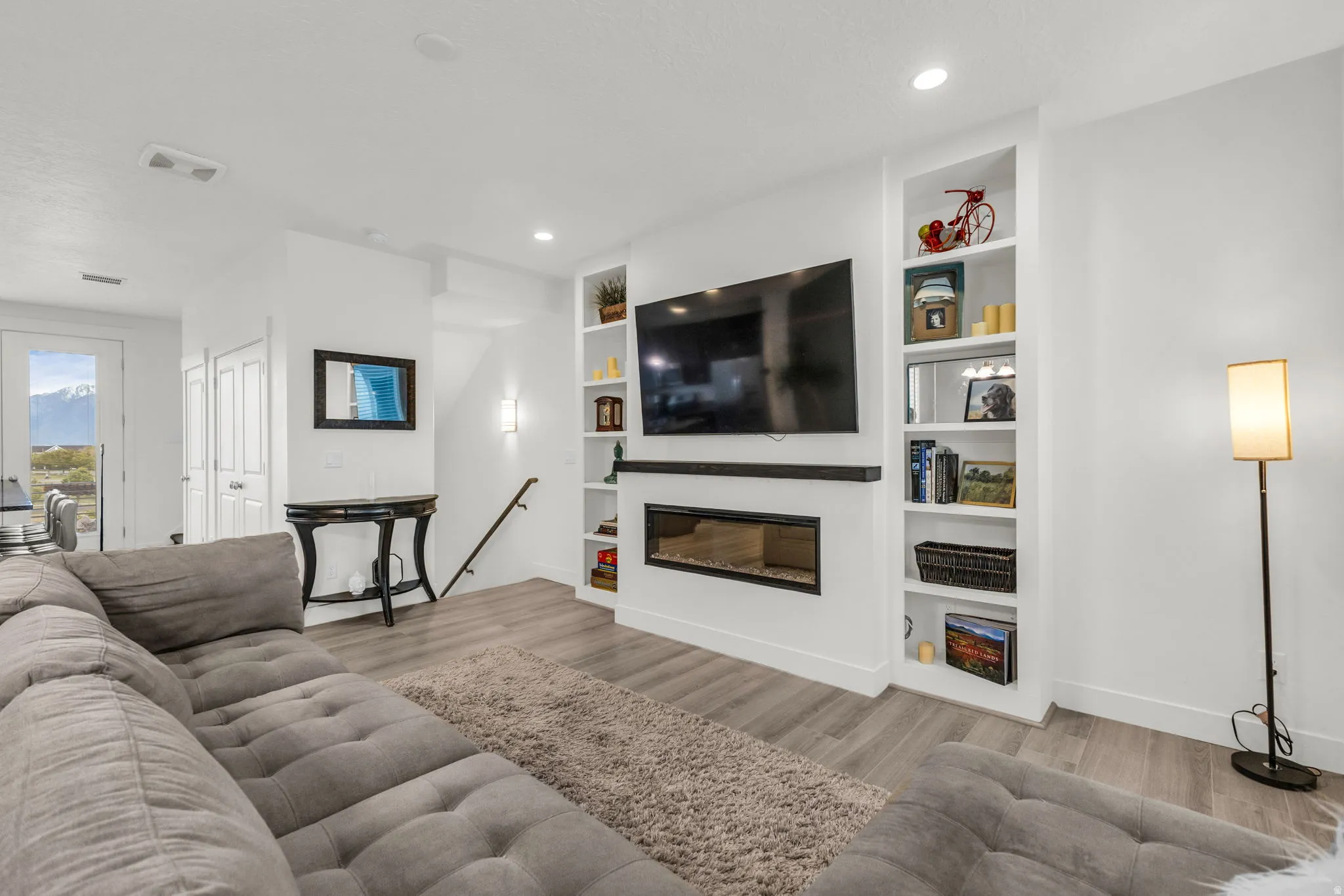 Living area featuring wood-finish flooring, recessed lighting, and an integrated electric fireplace