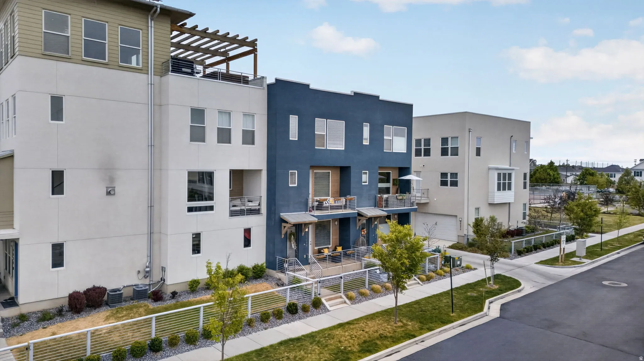 Modern multi-story townhome featuring a flat roofline and a rooftop deck with a wood pergola
