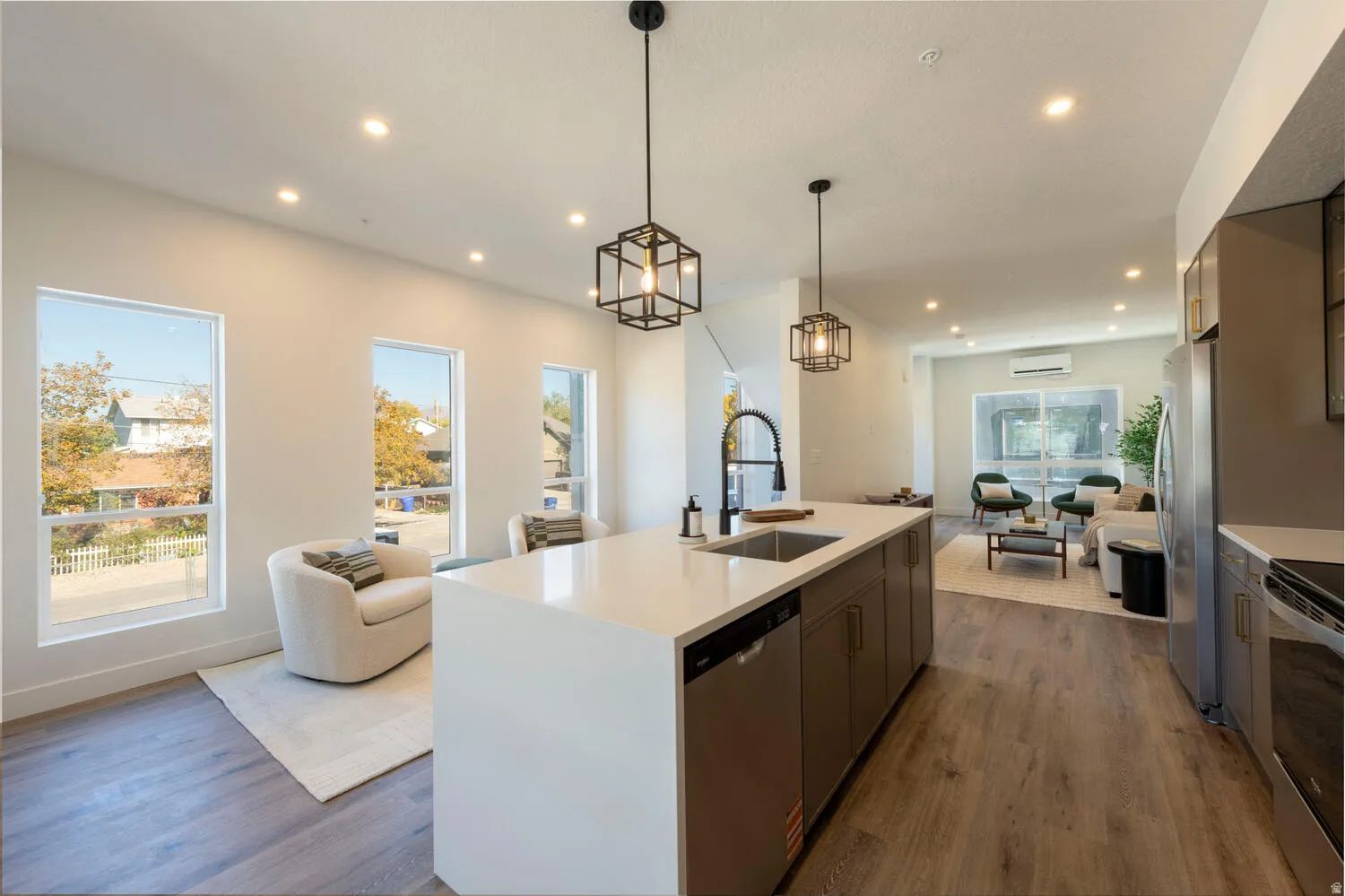 Open-concept kitchen featuring a large central island with an undermount sink, quartz countertop, and integrated dishwasher
