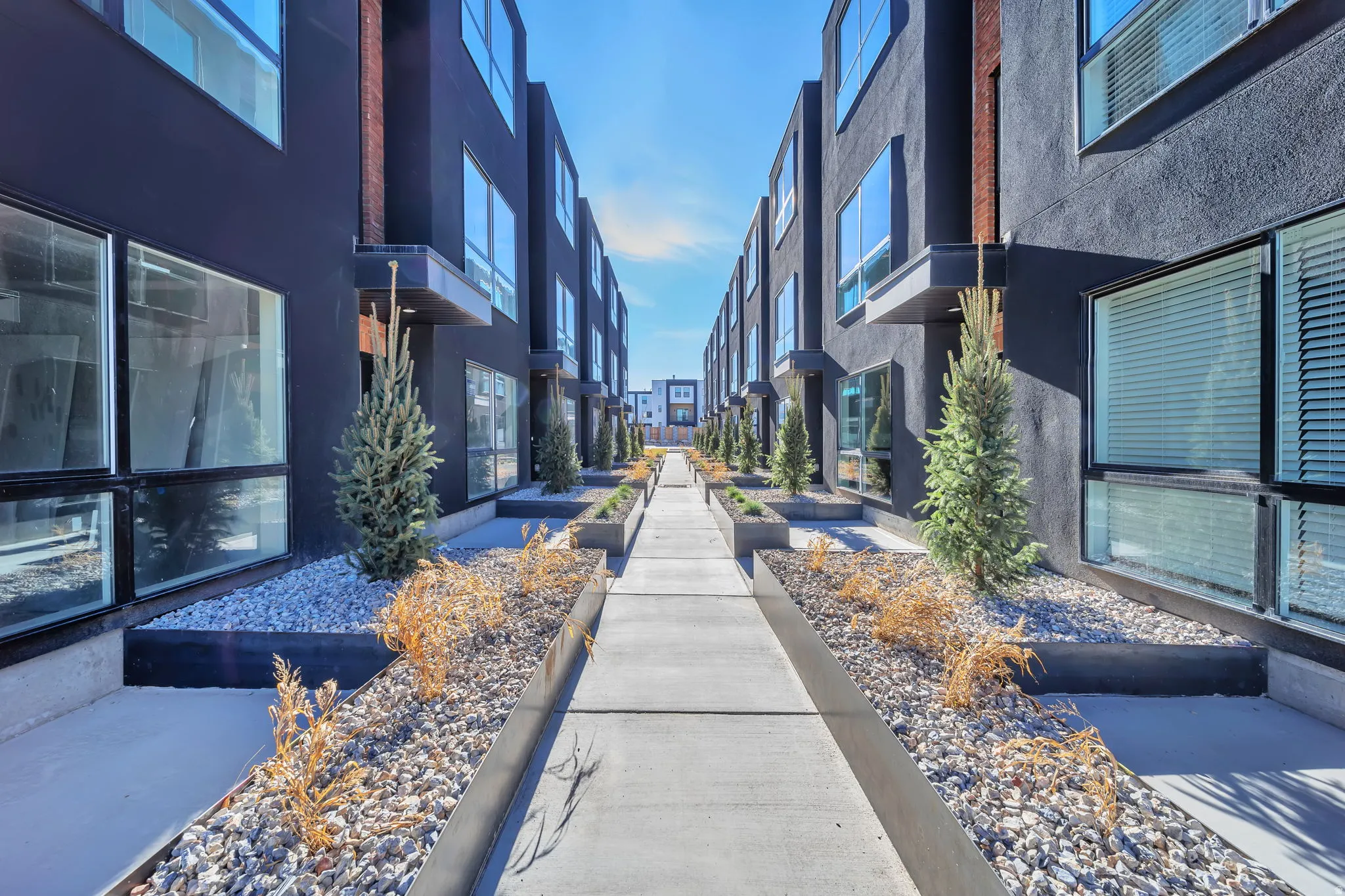 Modern townhome exteriors featuring dark stucco finishes and expansive windows