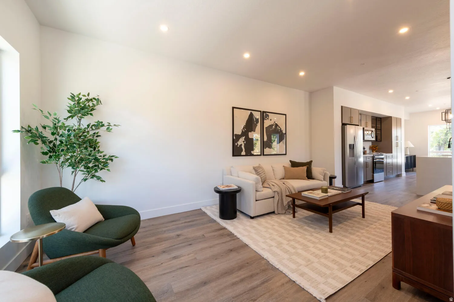 Open-concept living space featuring recessed lighting, wood-finish flooring, a bright window, and a kitchen with stainless steel appliances