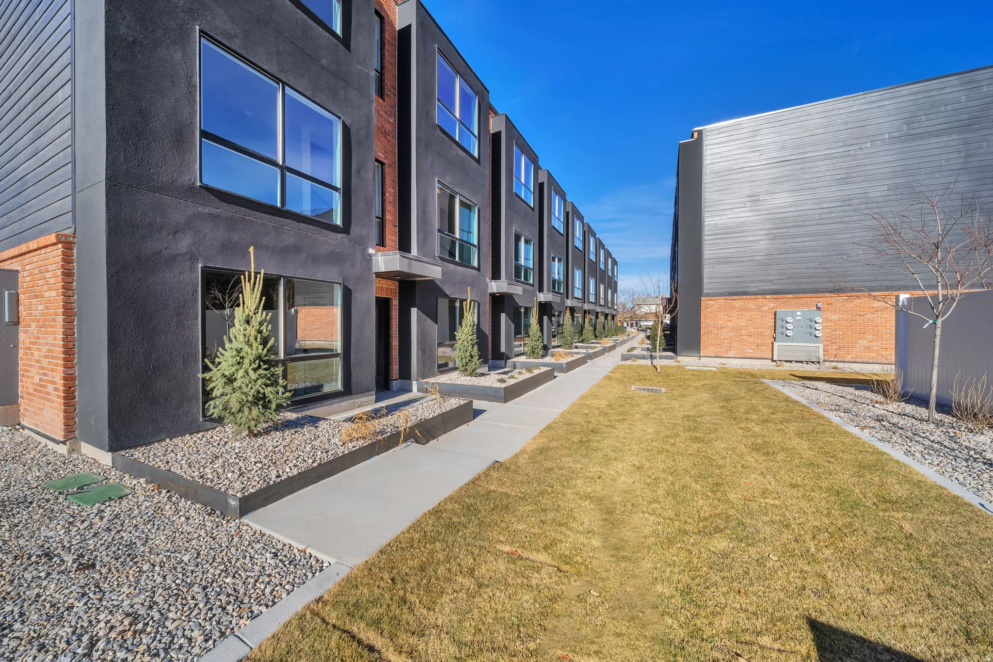 Contemporary townhome exterior featuring dark stucco and brick accents