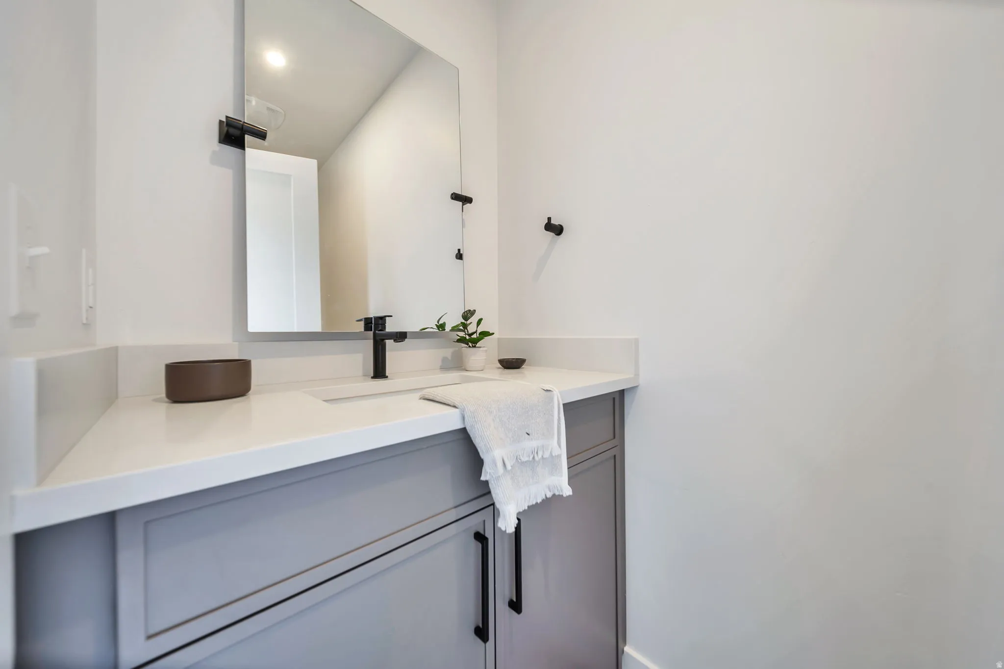 Contemporary vanity with a light gray shaker-style cabinet and integrated rectangular sink