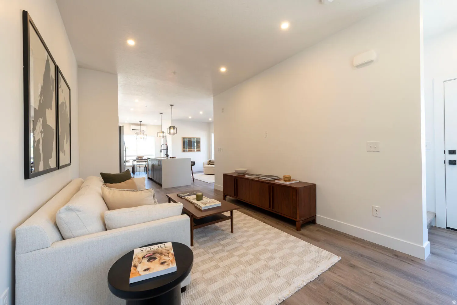 Open-concept living area with wood-finish flooring, recessed lighting, and white baseboards