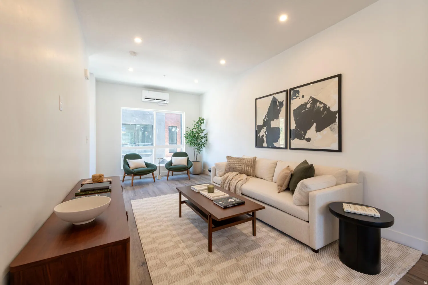 Open-concept living area featuring light-toned walls, recessed lighting, and wood-finish flooring