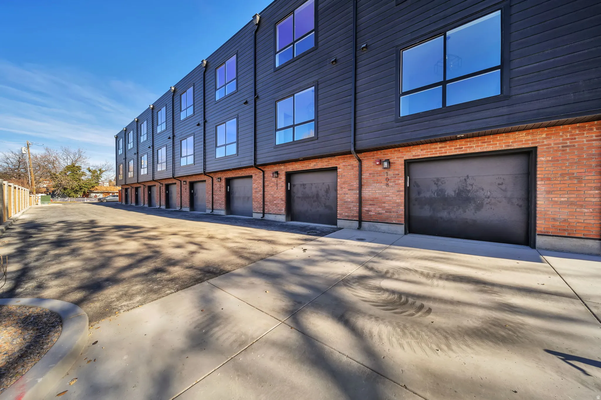 Modern townhome row featuring dark siding and red brick accents
