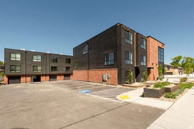 Modern multi-story building featuring black horizontal siding and brick accents