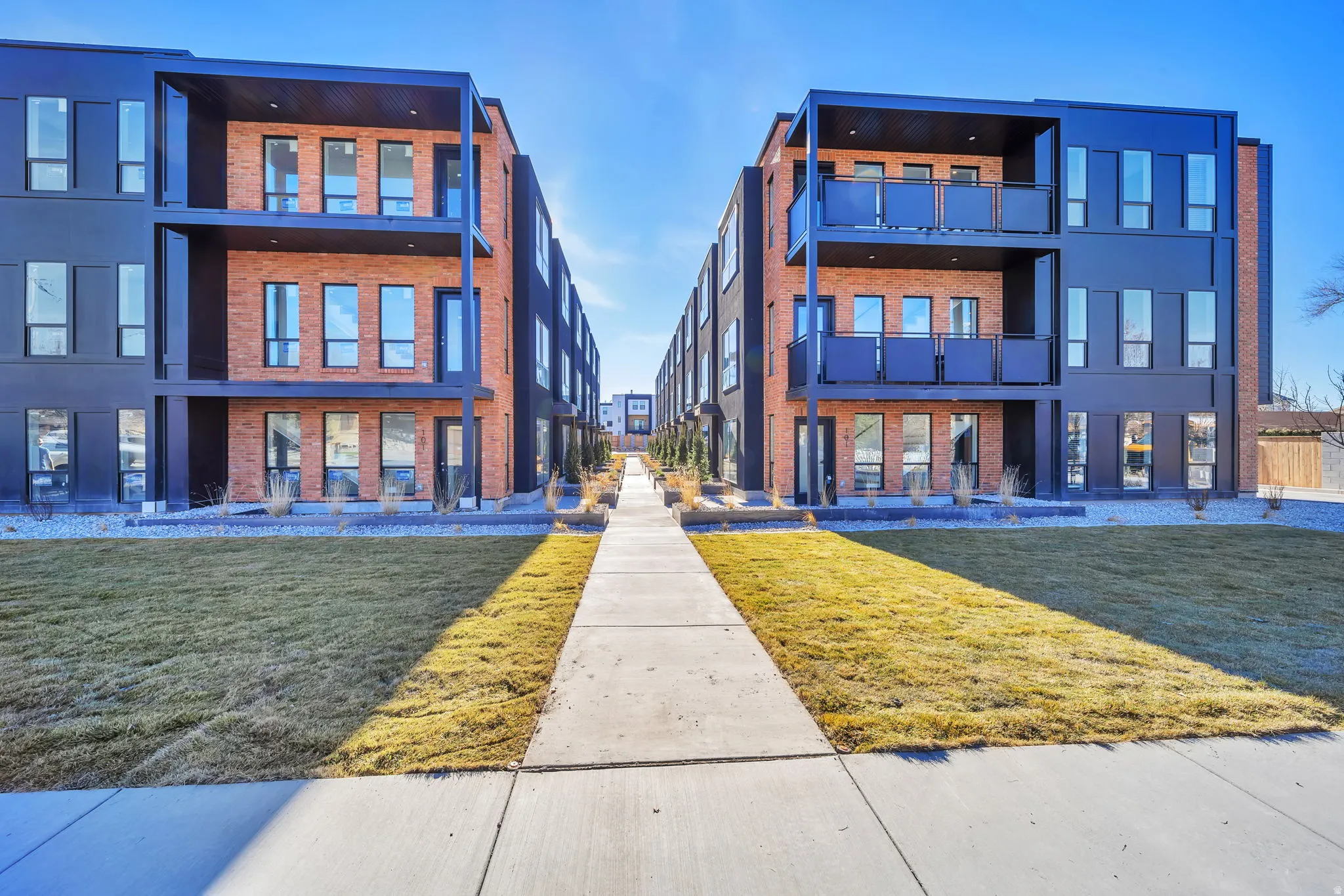 Modern multi-story buildings featuring a striking combination of red brick and dark-paneled facades