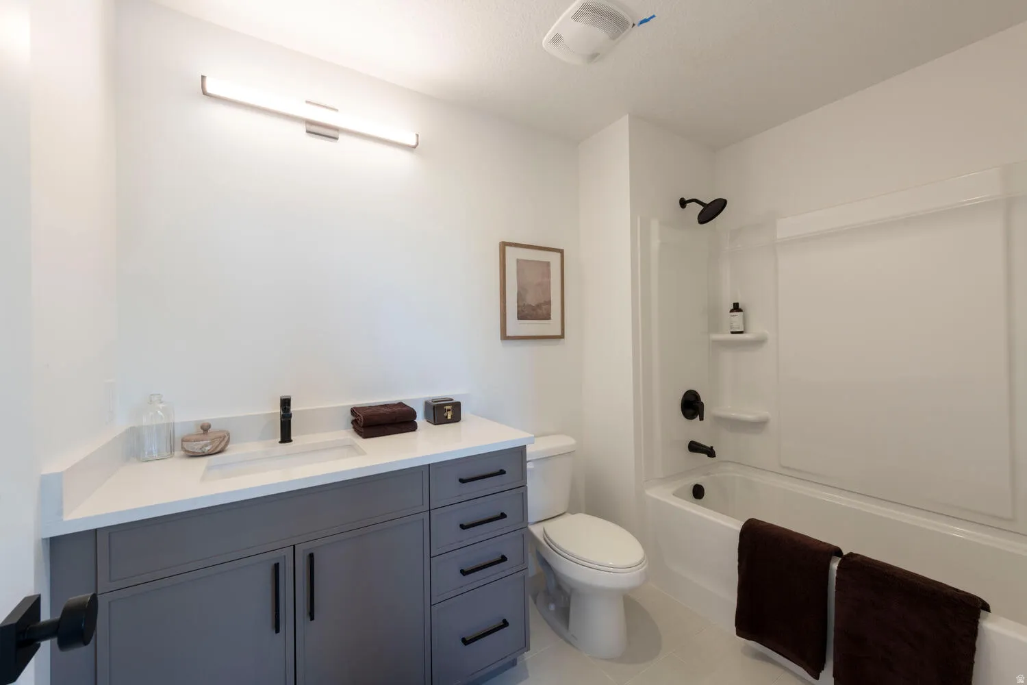 Modern bathroom featuring a single vanity with a white countertop and gray cabinetry