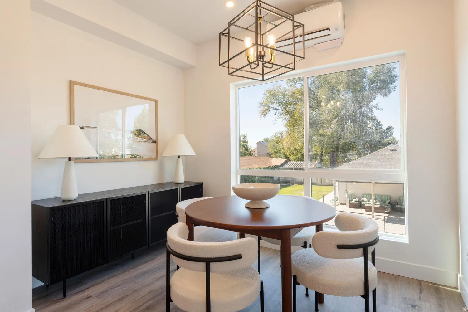 Bright dining area featuring a large window, wood-finish flooring, and a contemporary light fixture