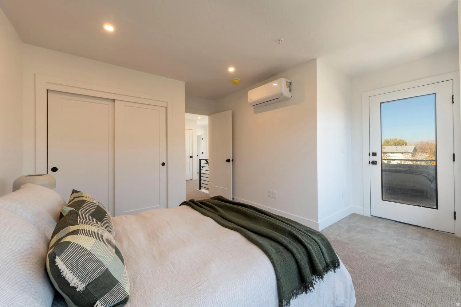 Bedroom featuring neutral carpeting, a glass-paneled door, and a built-in split-system air conditioning unit
