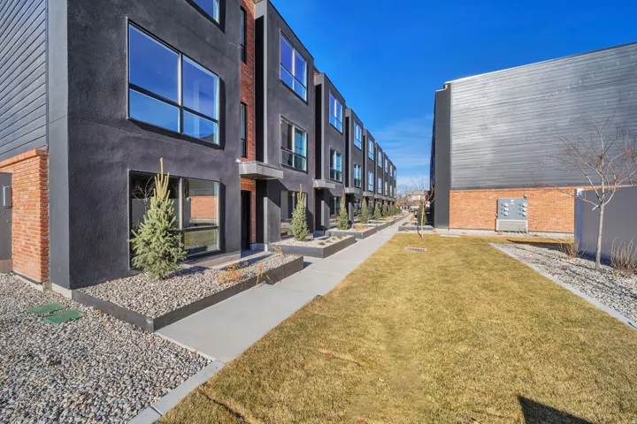 Contemporary townhome exterior featuring dark stucco and brick accents