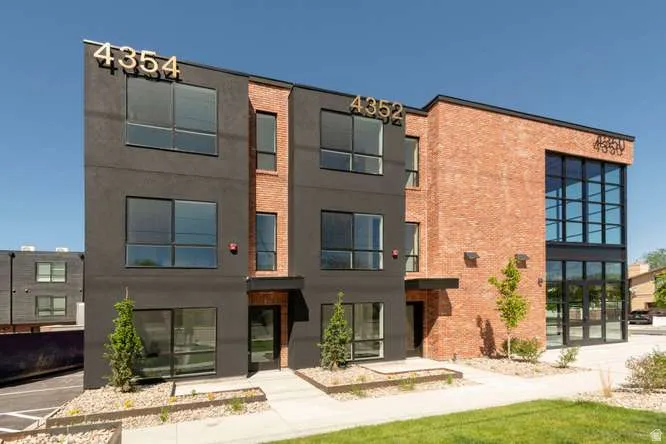 Contemporary multi-story building featuring a facade of dark paneling and red brick