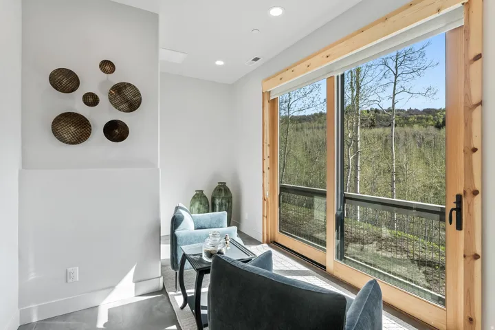 Expansive sliding glass doors with natural wood frames, offering abundant natural light and a broad outdoor perspective