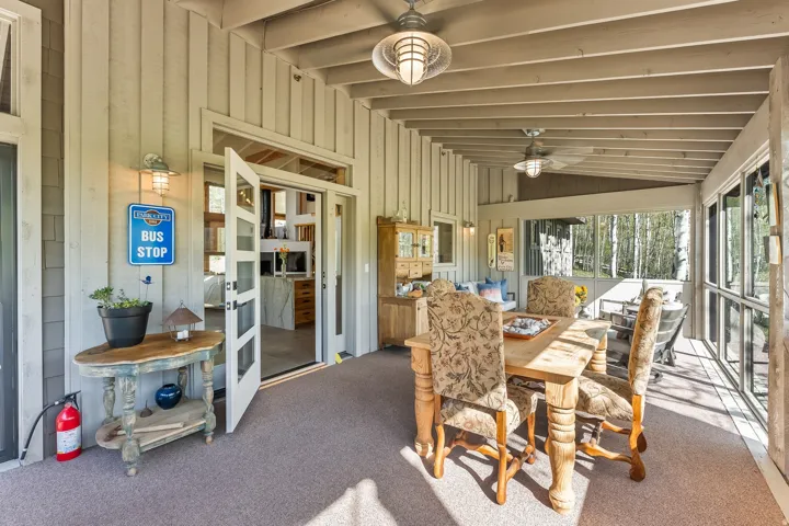 Screened-in patio with exposed beam ceiling, ceiling fans, and an exterior wall featuring vertical siding