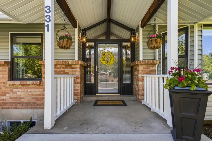 Inviting covered entryway featuring a full-light entry door, sidelights, transom windows, and dual exterior lanterns