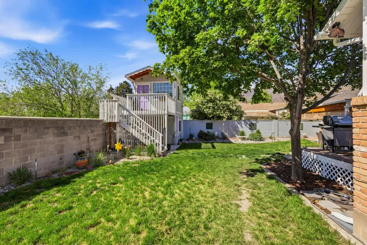 Expansive green lawn with a multi-level deck structure featuring a private room above