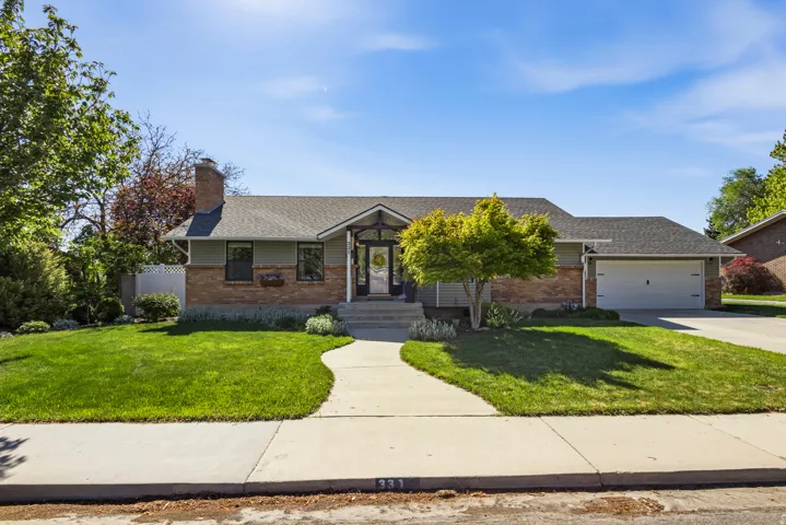 Ranch-style residence featuring a brick facade with horizontal siding, a gabled entry, an attached garage, a front lawn, and a concrete driveway