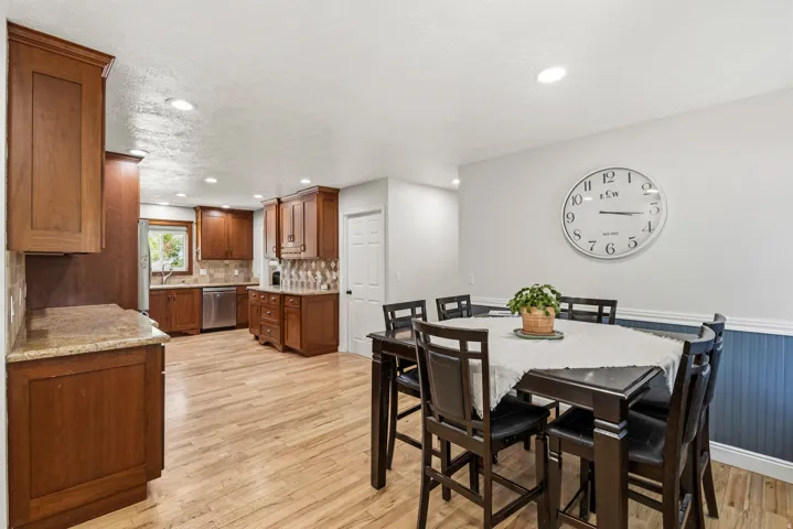 Open-concept kitchen and dining area featuring wood-finish flooring, recessed lighting, and rich wood cabinetry