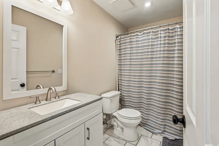 White framed mirror above a vanity with a light-toned countertop and an undermount sink