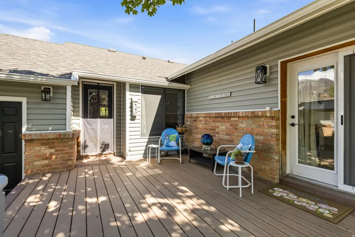 Spacious wood-finish deck with a glass-paned exterior door, brick accent wall, and horizontal siding
