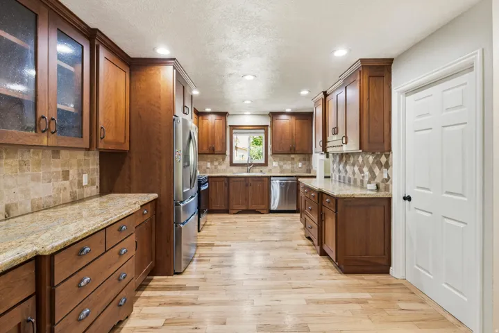 Spacious kitchen featuring extensive wood cabinetry, light-toned wood-finish flooring, and recessed lighting