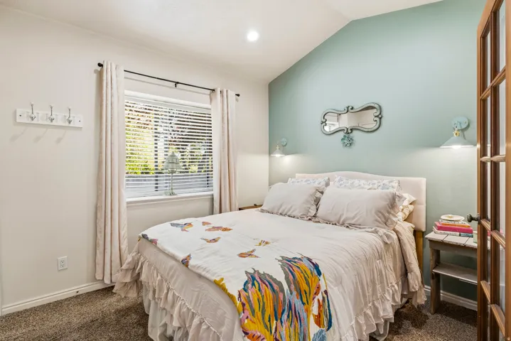 Vaulted ceiling bedroom featuring plush carpet flooring