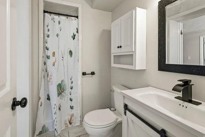 Bathroom featuring a white vanity with barn door style cabinetry, a black waterfall faucet, and a rectangular sink