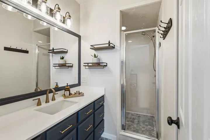 Bathroom vanity featuring a single basin, brass-finish faucet, and dark cabinetry with brass-tone hardware