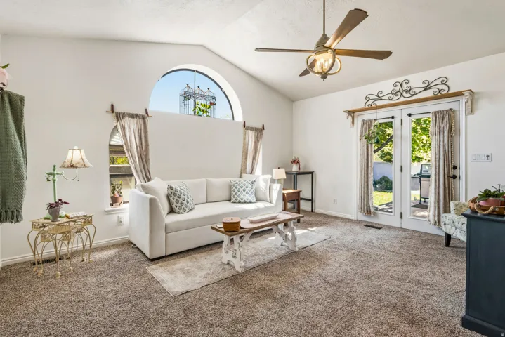 Living area featuring vaulted ceilings, a large arched window, and French doors