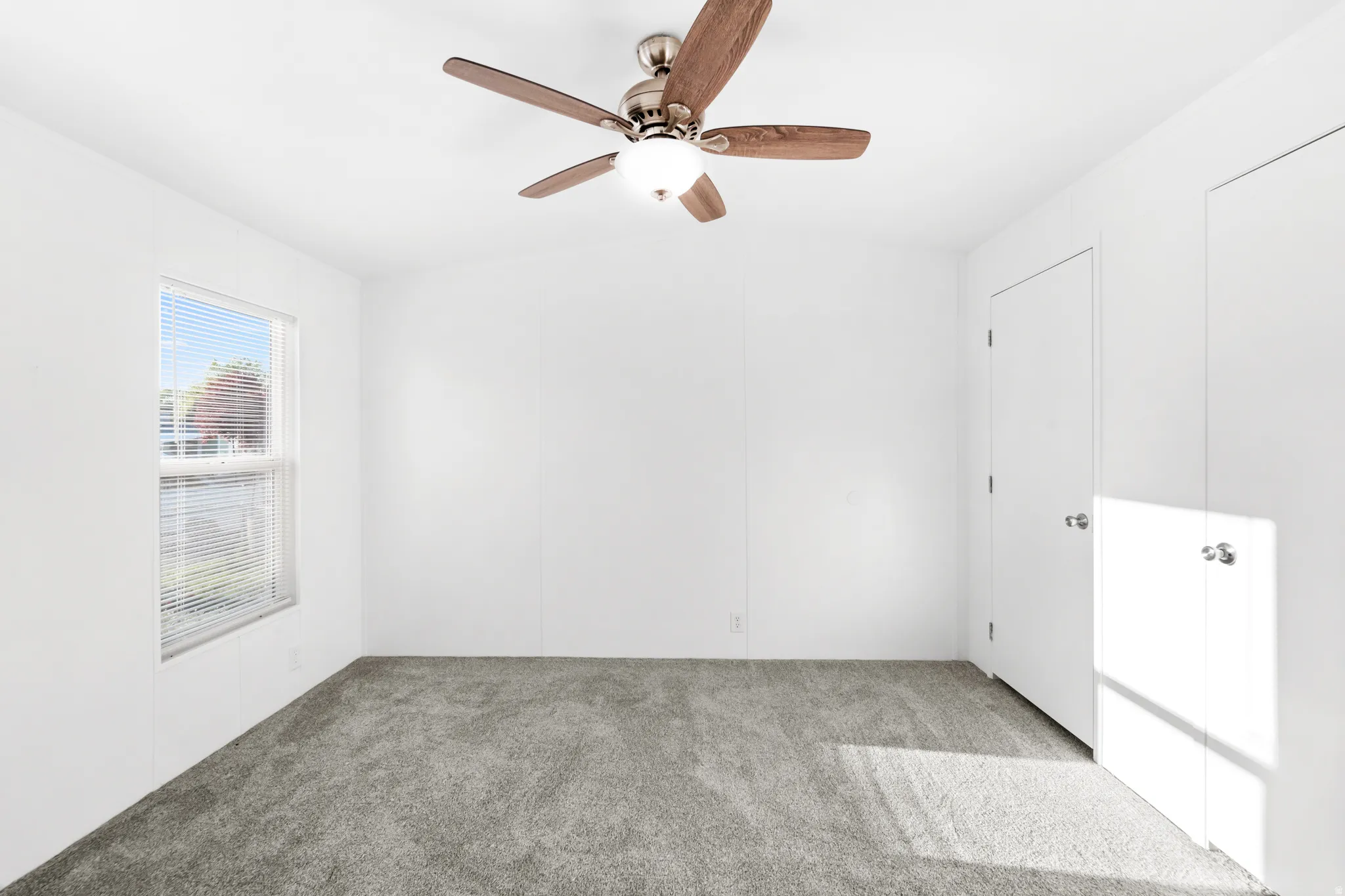 Neutral white walls complemented by a vaulted ceiling with a ceiling fan