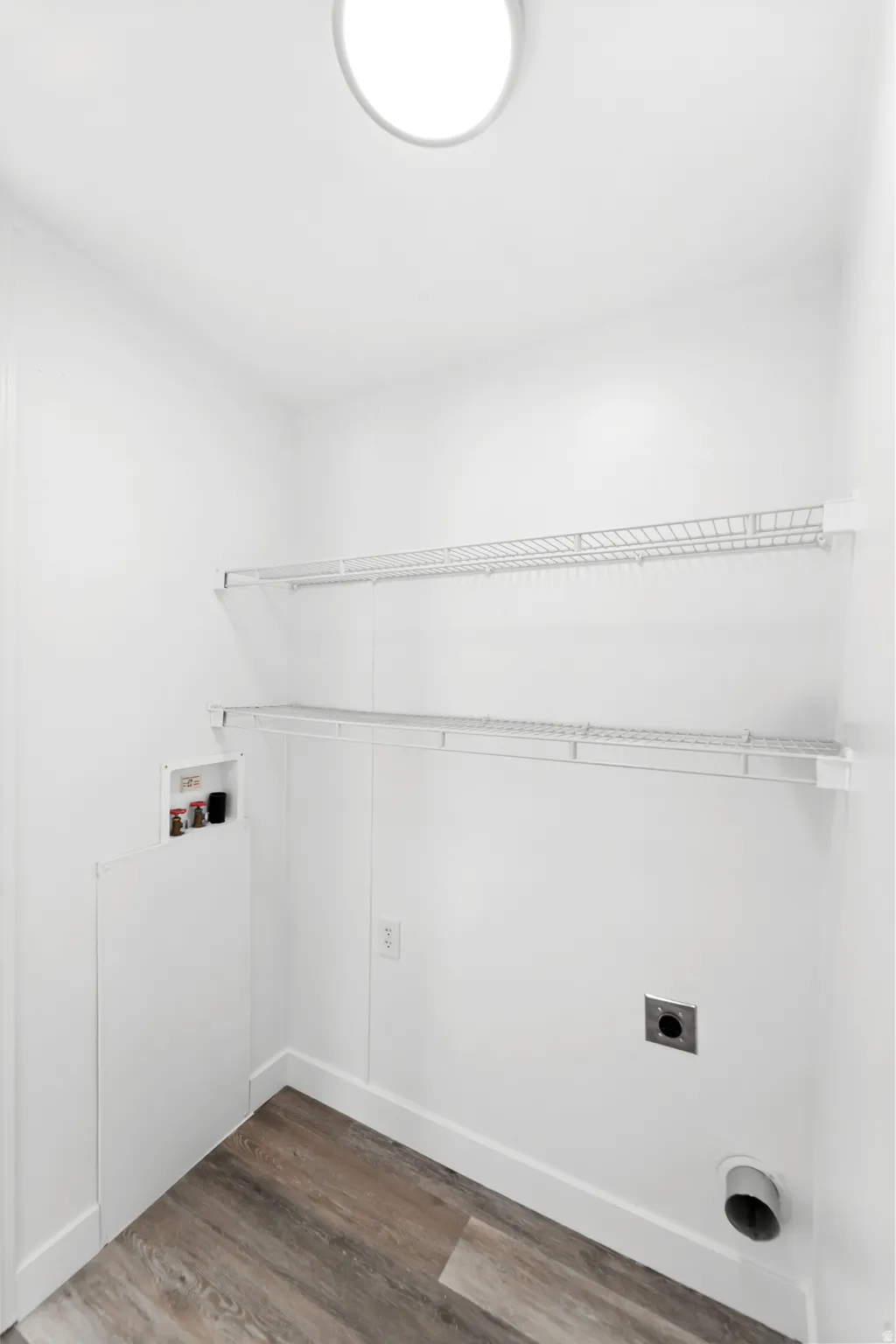Dedicated utility space featuring wood-finish flooring, white baseboards, and bright white walls