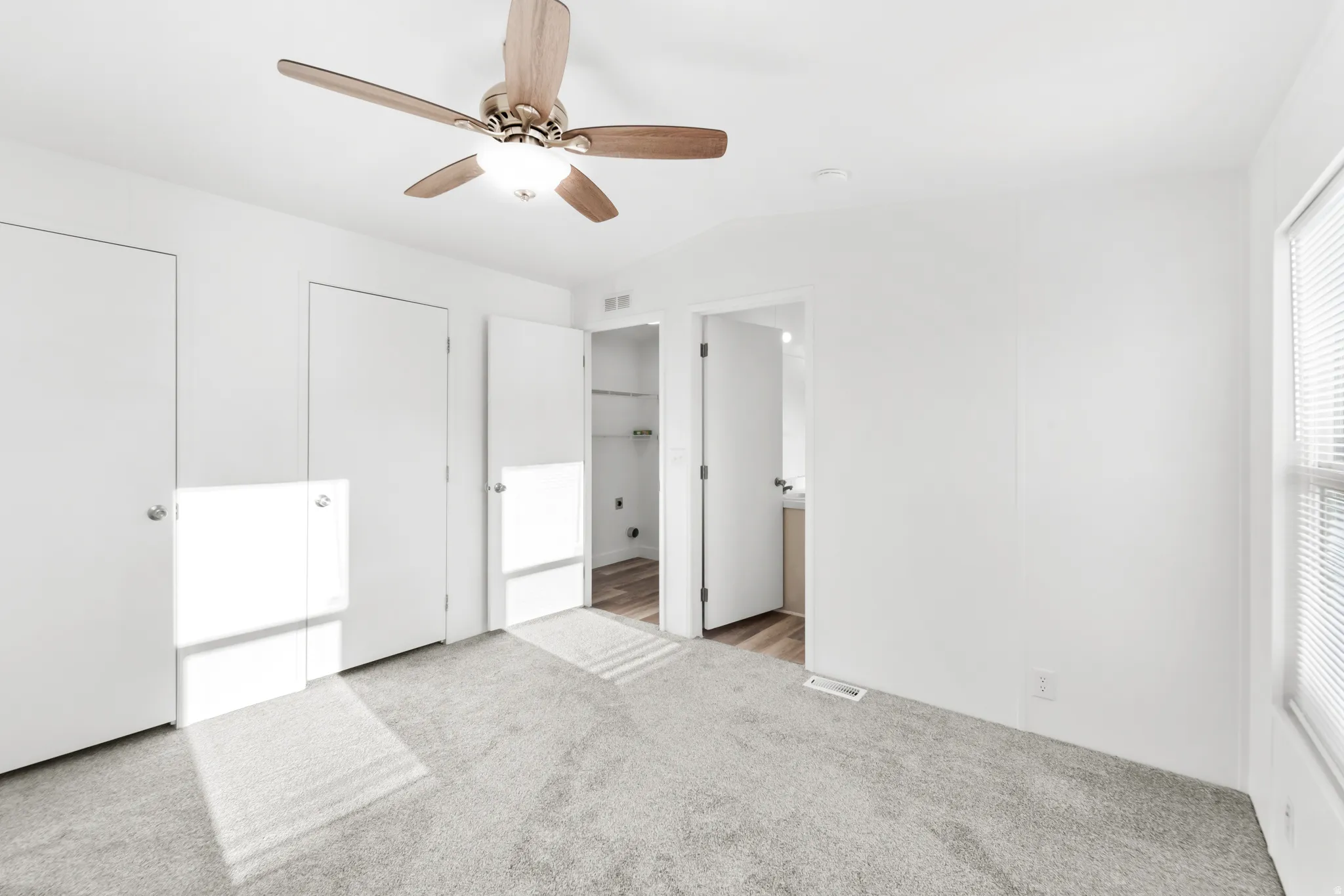 Carpeted bedroom with a wood-finish ceiling fan and light fixture