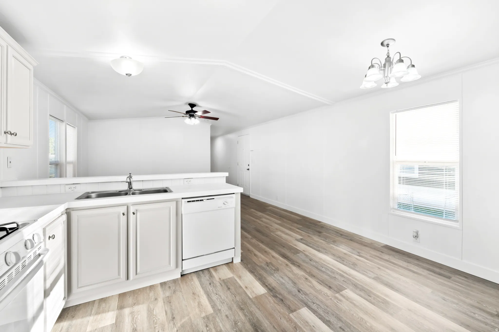 Kitchen area featuring white cabinetry, a double basin sink, and a built-in dishwasher
