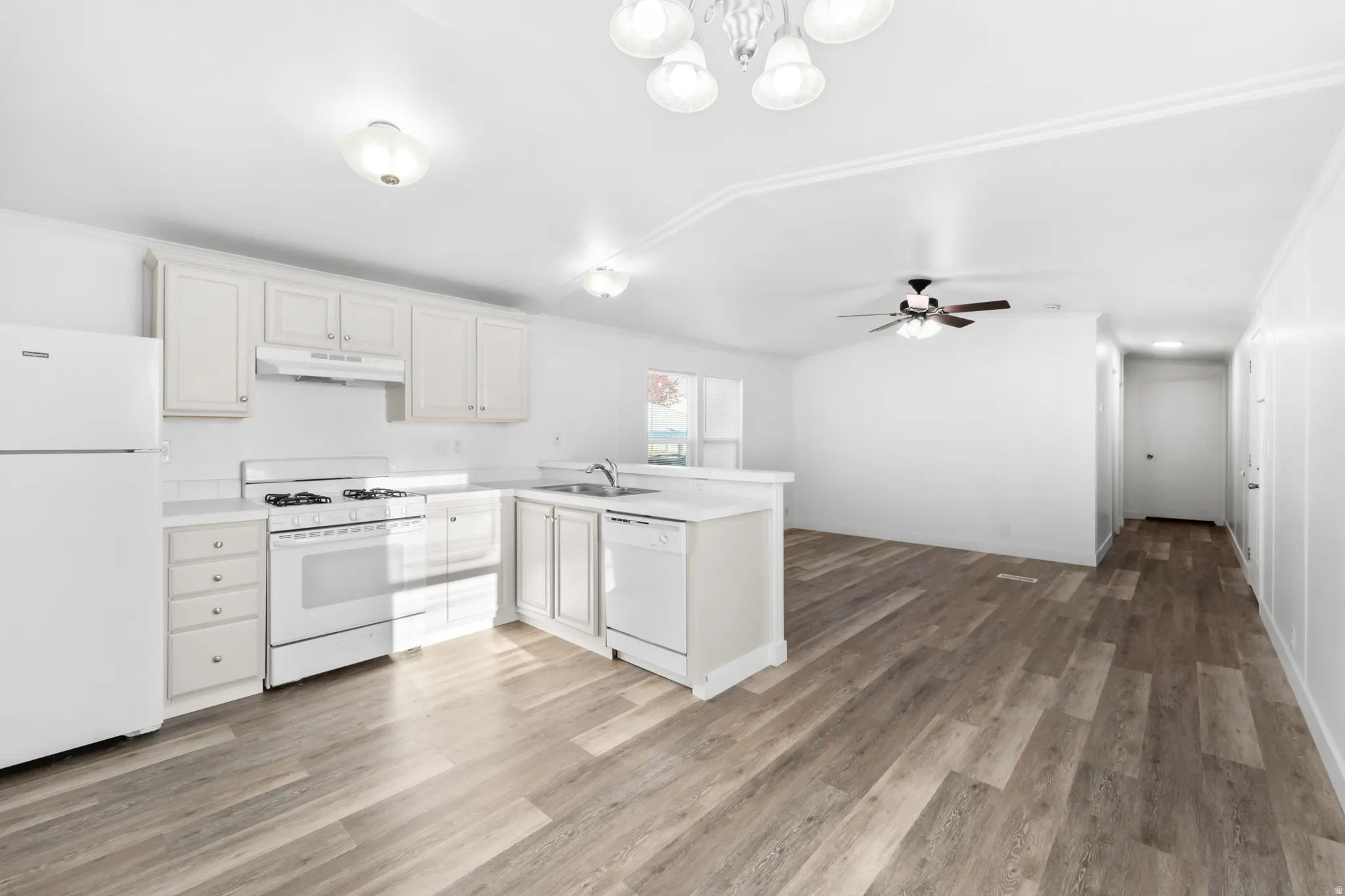 Kitchen featuring white cabinetry, white appliances, laminate countertops, and wood-finish flooring