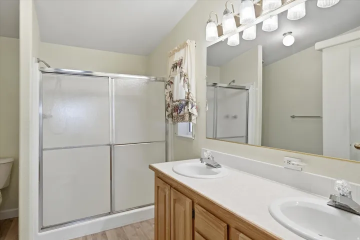 Bathroom featuring a dual vanity with integrated sinks, wood-finish cabinetry, and a full-width mirror with overhead lighting