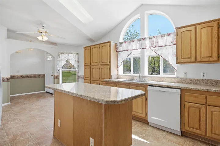 Kitchen featuring a center island with a speckled countertop, extensive wood cabinetry, and a double basin sink