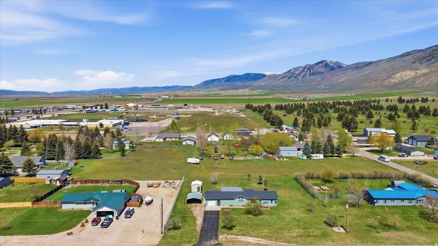 Aerial perspective showcasing a residential property with a detached garage, a gravel driveway, and a fenced yard