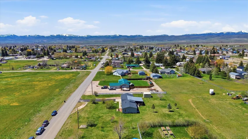 Expansive property featuring verdant fields, multiple outbuildings, and a gravel road frontage