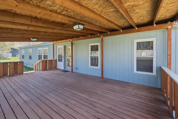 Expansive covered deck featuring wood-finish decking, exposed wood beams, and recessed lighting