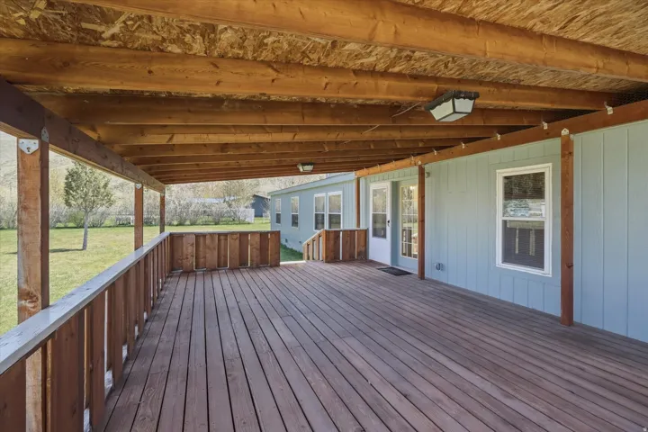 Expansive covered deck featuring wood-finish flooring, a wood railing, and exposed wood ceiling beams