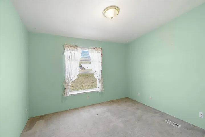 Room featuring light green walls, a single window, and a ceiling-mounted light fixture