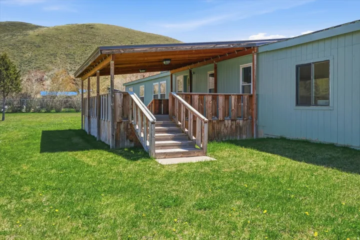 Expansive green lawn with a covered porch featuring wooden railings and steps