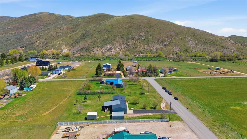 Expansive undeveloped parcel featuring a mountainous backdrop, green fields, and a paved road