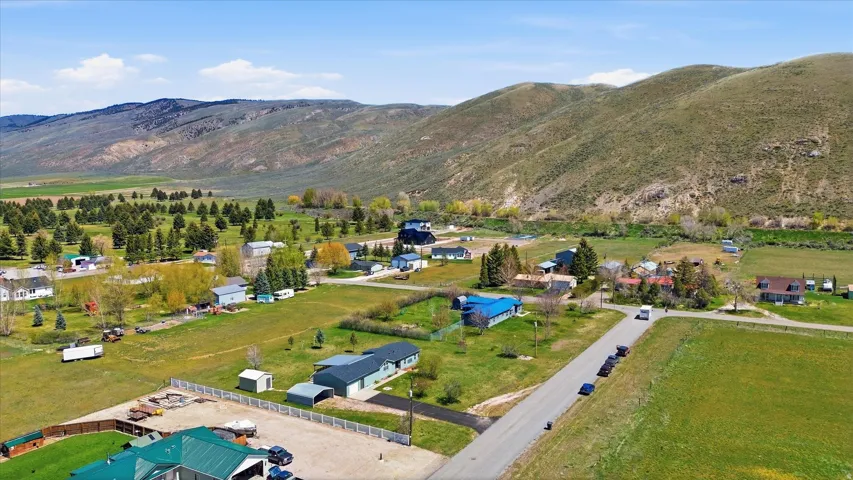 Expansive land with a mountain backdrop, mature trees, and open green spaces