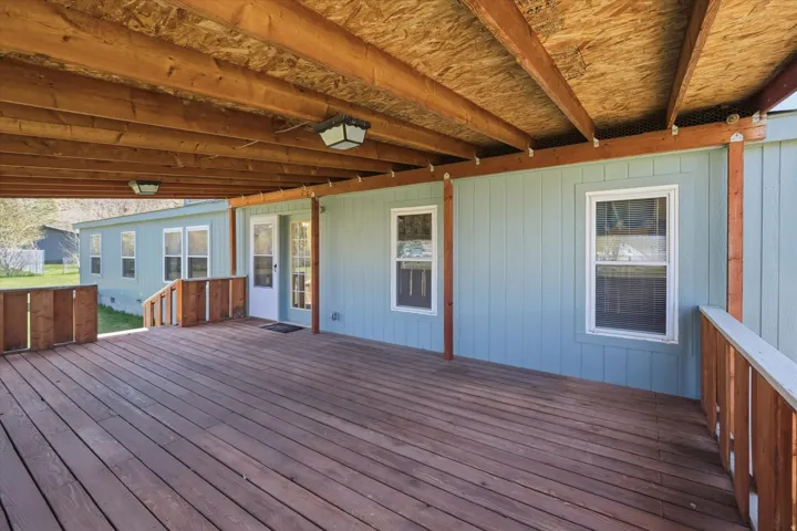 Expansive covered deck featuring wood-finish flooring, exposed wood beams, and recessed lighting