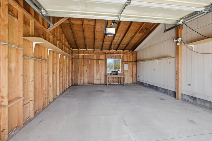 Spacious garage featuring a concrete floor, exposed wood beam ceiling, and a single window