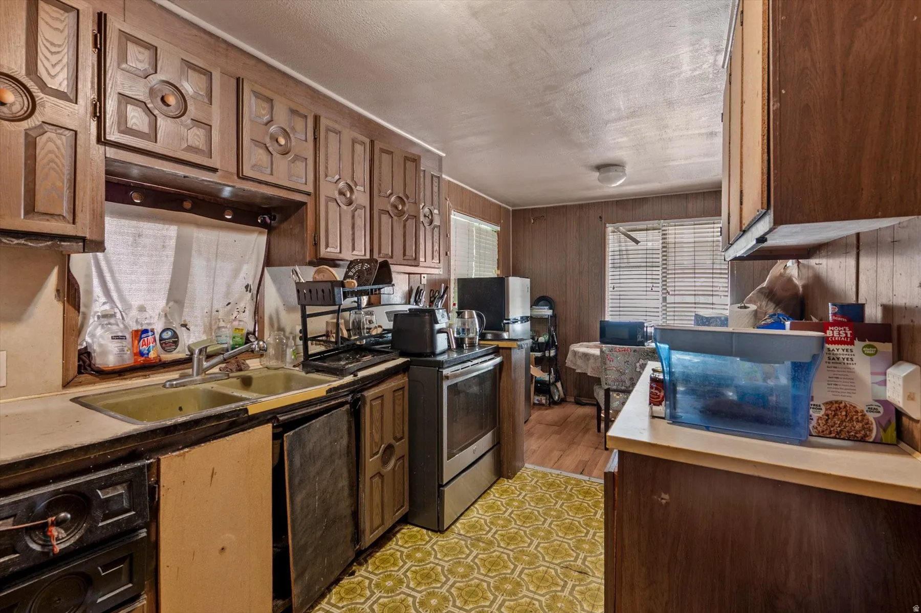 Kitchen area featuring wood-paneled walls and a window with blinds