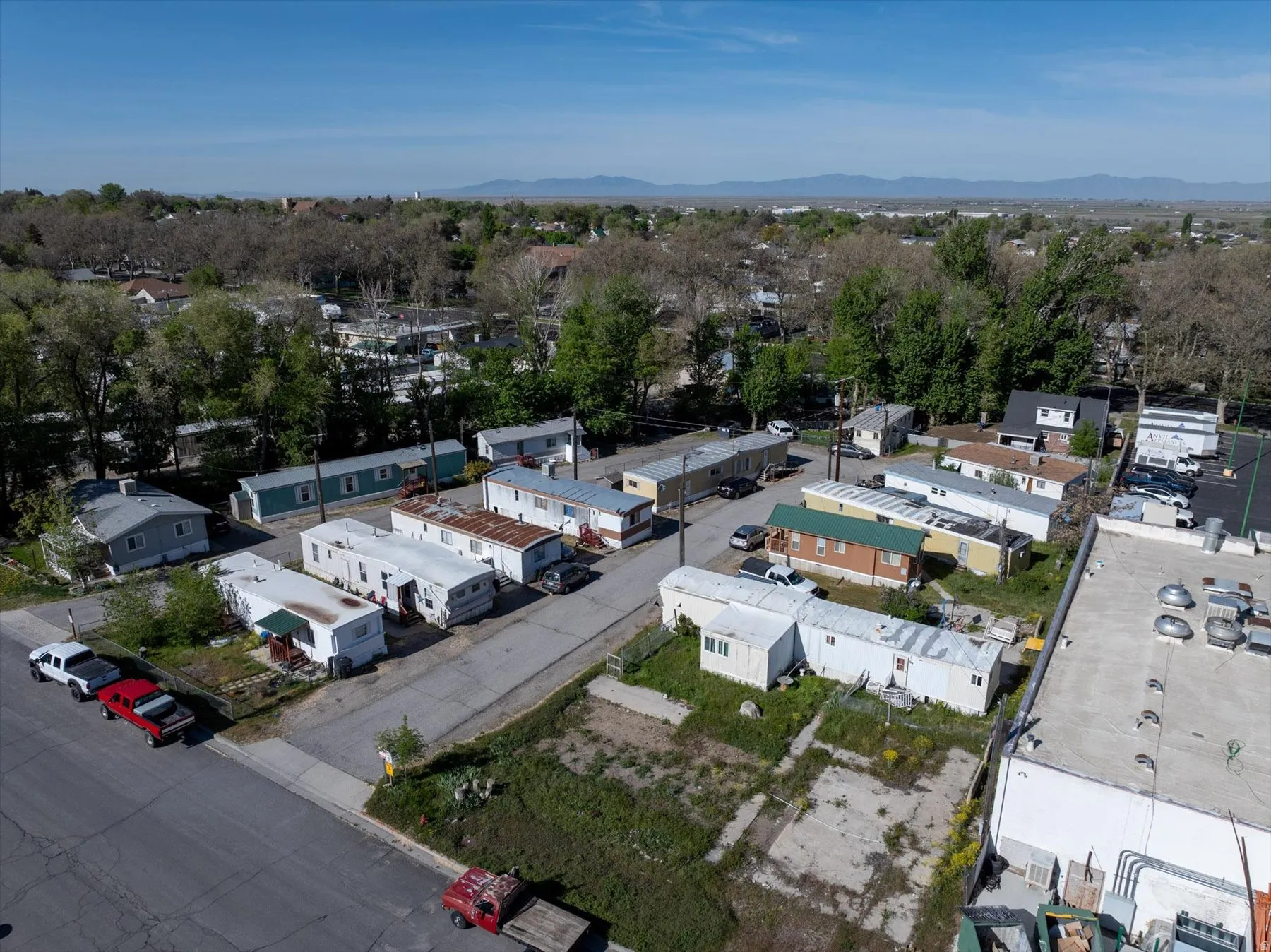 Aerial perspective showcasing a mobile home community with multiple units, paved roadways, and surrounding mature trees
